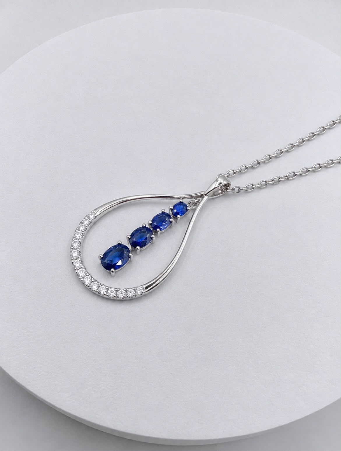 Pendant set with graduated blue sapphires on a white gold chain